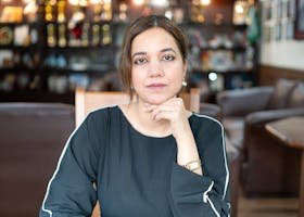Portrait of a confident woman seated indoors with a thoughtful expression in Islamabad.